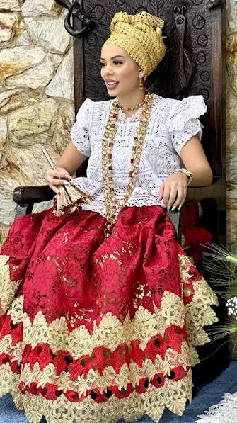 Yalasé Isa de Logunede, trajada de baiana, com colares dourados